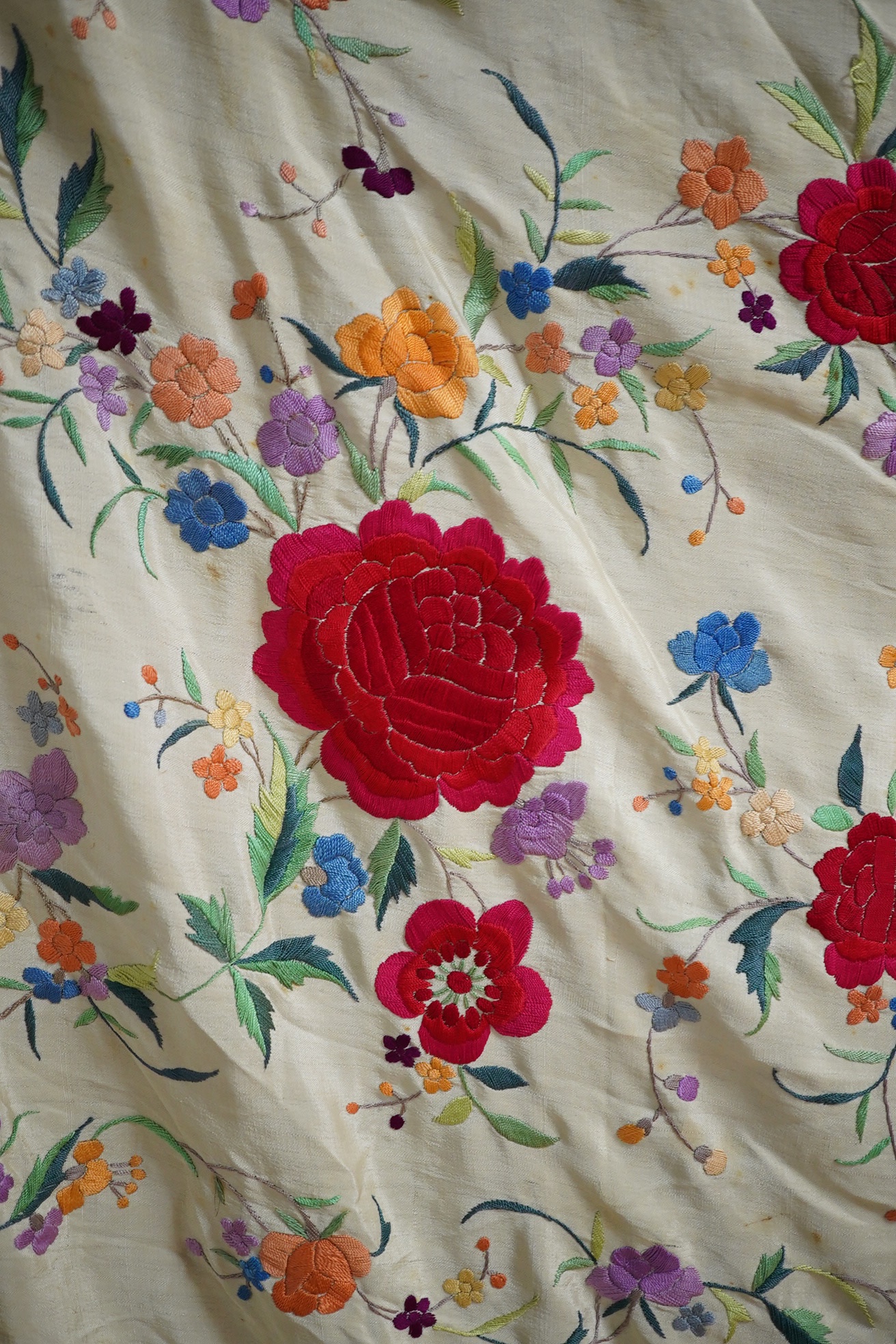 A late 19th / early 20th century Chinese cream silk and polychrome floral embroidered tasselled shawl, embroidered with a rose and floral all over design in a multitude of colours on a plain cream silk background with lo